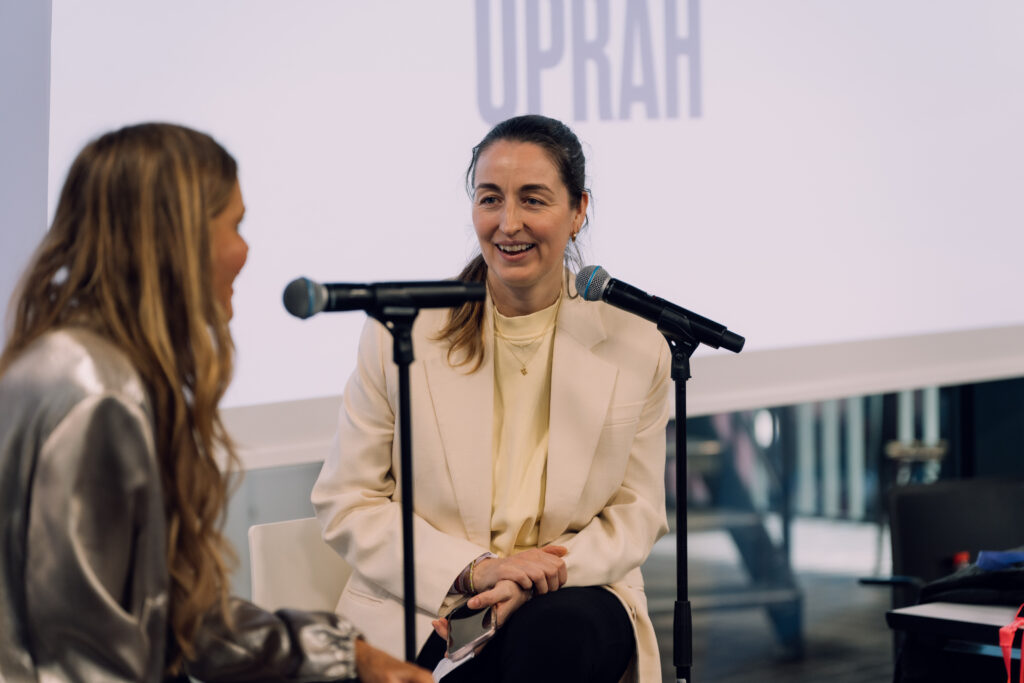 Henrike Redecker im hellen Blazer spricht auf einem Panel vor Mikrofonen.